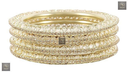 Golden kada set with artificial pearls and zircon gemstones in an intricate curved pattern.