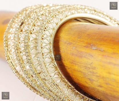 Golden kada set with artificial pearls and zircon gemstones in an intricate curved pattern.